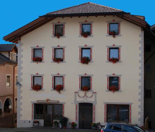 a large white building with red shuttered windows at gasthof pension rössl in Nova Ponente