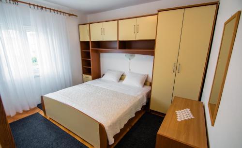 a bedroom with a bed and cabinets and a table at Apartments Picolo Paradiso Miljenko Debelić in Rab