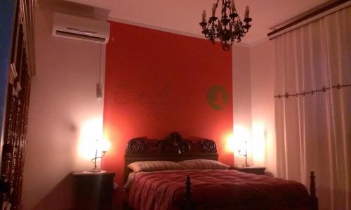 a bedroom with a red wall with a bed and two lamps at B&B Itala in Recanati