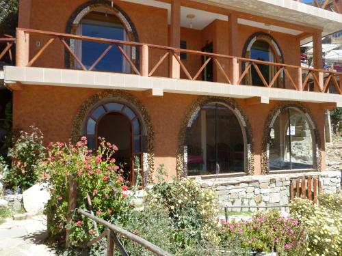 a house with a balcony on top of it at Hostal Phaxsi in Comunidad Yumani