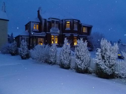 a large house in the snow at night at Greenlaw Guest House in Gretna Green