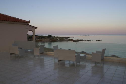 a patio with a table and chairs next to the water at Ammos Residence in Minia
