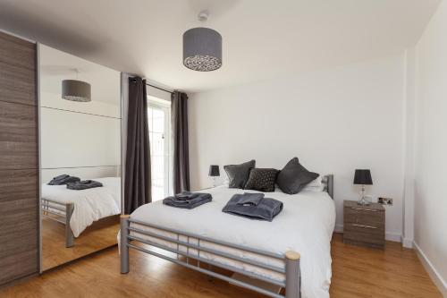 een witte slaapkamer met een bed en een spiegel bij Stunning Contemporary Apartment - Free Parking - 5 Minute Walk To The Beach - Great Location - Fast WiFi - Smart TV With Netflix Included - Perfect For Short and Long Stays in Bournemouth