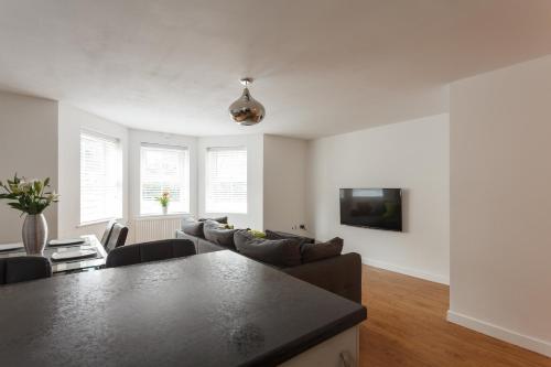 a living room with a couch and a table at Stunning Contemporary Apartment - Free Parking - 5 Minute Walk To The Beach - Great Location - Fast WiFi - Smart TV With Netflix Included - Contractor Friendly - Perfect For Short and Long Stays in Bournemouth