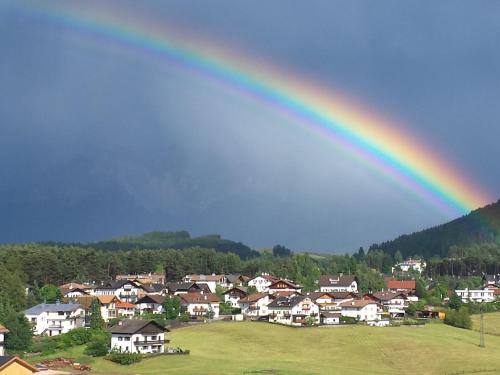 a rainbow in the sky over a town with houses at gasthof pension rössl in Nova Ponente