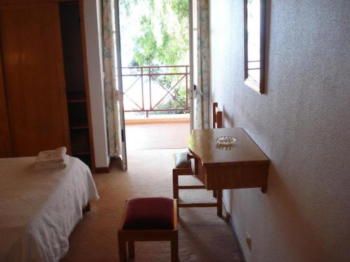 a bedroom with a bed and a desk and a window at AL Moniz in Machico