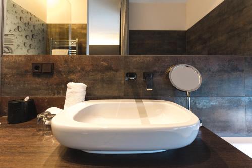 a white tub in a bathroom with a mirror at SAKS Urban Design Hotel Kaiserslautern in Kaiserslautern