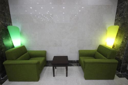 two green chairs and a table in a room at Jana Palace Serviced Apartments in Jeddah