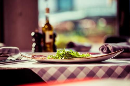 a plate of salad on a table with a bottle of wine at SAKS Urban Design Hotel Kaiserslautern in Kaiserslautern