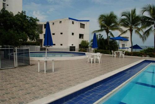 una piscina con sillas y sombrillas junto a un edificio en Apartamento con playa privada y piscina, en Santa Marta