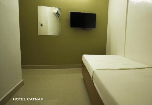 a room with two beds and a tv on the wall at Hotel Catnap in Mettuppālaiyam