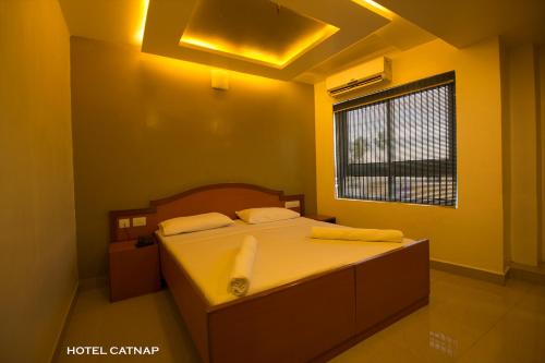 a bedroom with a bed with yellow walls and a window at Hotel Catnap in Mettuppālaiyam