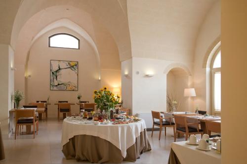 a dining room with a table with flowers on it at Corte Borromeo in Manduria