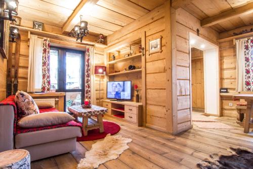 a log cabin living room with a tv and a couch at Apartament Kominkowy Deluxe Zakopane in Zakopane