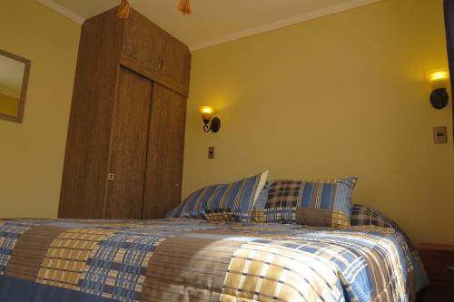 1 dormitorio con 1 cama con manta azul y blanca en Cabañas Vikurayen en Olmué