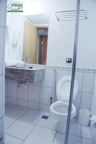 a white bathroom with a toilet and a sink at Prime Hotel Águas da Serra in Rio Quente