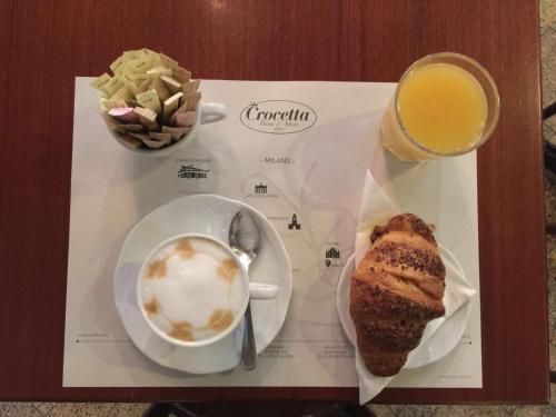 a table with a cup of coffee and a plate of food at Duomo Rooms in Milan