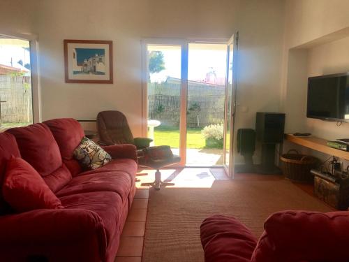 a living room with a red couch and a television at Vila Mar in Porto Covo