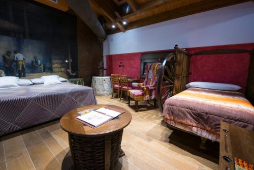 a room with two beds and a table and chairs at Hotel SPA El Lagar de Isilla in La Vid y Barrios