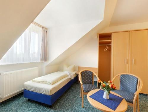 a hotel room with a bed and two chairs at Hotel Jagermo in Grasbrunn