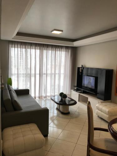 ein Wohnzimmer mit einem Sofa und einem TV in der Unterkunft Apartamento Central 2 Quartos in Balneário Camboriú