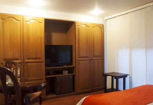 a room with a tv and wooden cupboards at Apartaestudios Los Andes in Bogotá