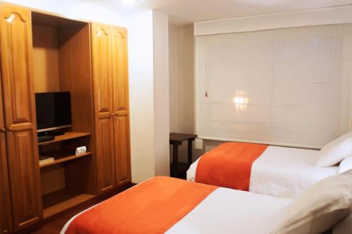 a hotel room with two beds and a television at Apartaestudios Los Andes in Bogotá