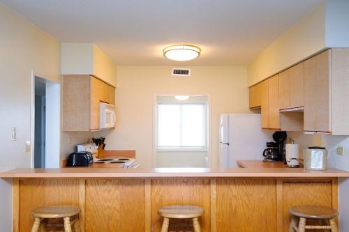 a kitchen with wooden cabinets and a counter with stools at The Sea Ranch Resort in Kill Devil Hills