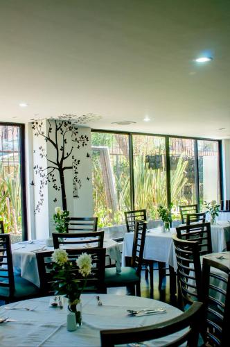 a dining room with white tables and chairs and windows at Apartaestudios Los Andes in Bogotá