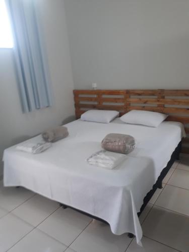 a white bed with two pillows on top of it at Flat Econômico Uberlândia in Uberlândia