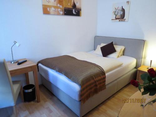 a small bedroom with a bed and a table at Hotel Saarblick Mettlach in Mettlach