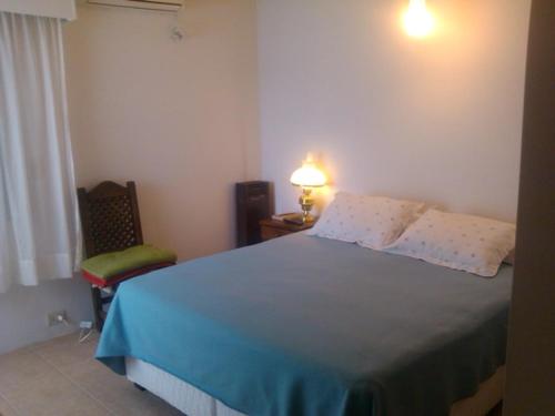 ein Schlafzimmer mit einem Bett, einem Stuhl und einer Lampe in der Unterkunft Casa en la Ruta del Vino in Mendoza