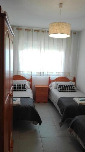 sypialnia z dwoma łóżkami i dużym oknem w obiekcie Apartamentos Loyo w mieście Portomarin