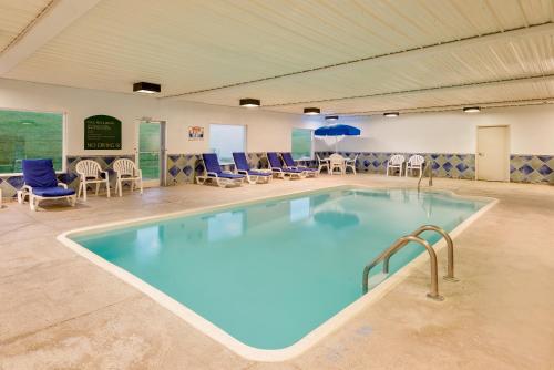 een groot zwembad in een kamer met stoelen en tafels bij Baymont by Wyndham Lawrenceburg in Lawrenceburg
