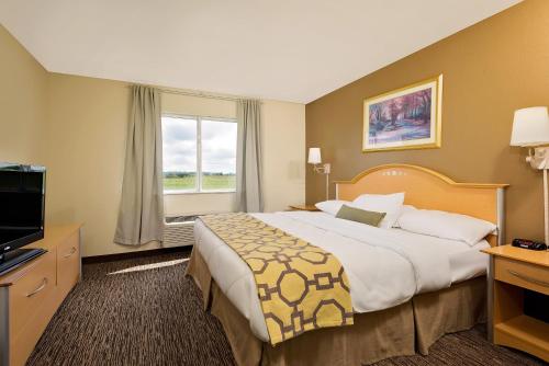 a hotel room with a large bed and a television at Baymont by Wyndham Lawrenceburg in Lawrenceburg