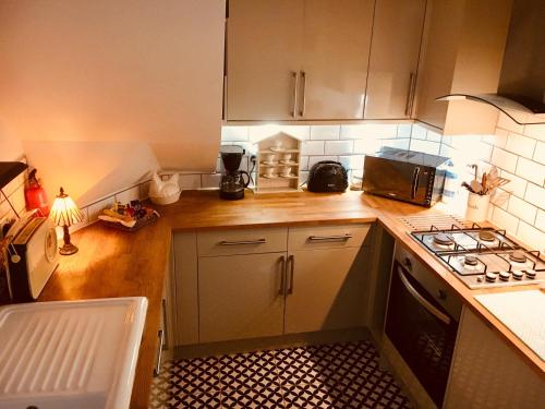 a small kitchen with a stove and a microwave at Dugdales Cottage in Settle
