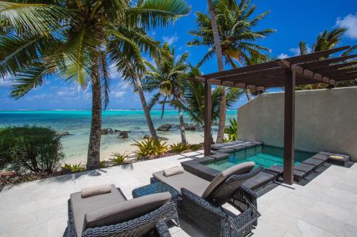 a resort patio with chairs and a swimming pool at Te Manava Luxury Villas & Spa in Rarotonga