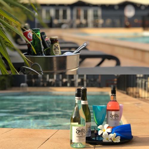 two bottles of beer sitting on a table next to a swimming pool at Best Western Plus The Ranges Karratha in Karratha