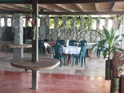 un restaurante con mesas y sillas y una pared de piedra en Cabañas Refugio Salomon en Nuquí