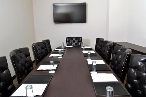 a conference room with a long table and black chairs at Hotel 5 de Mayo in Puebla