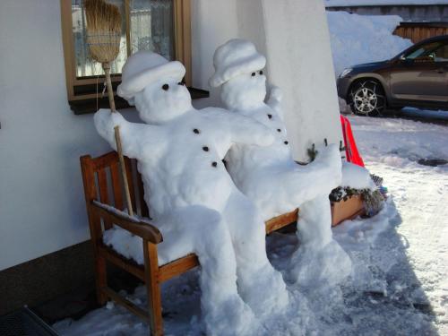 three snow people sitting on a chair in the snow at Landhaus Steiner in Schladming