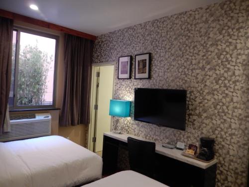 a hotel room with a bed and a desk with a tv at Quality Inn near Sunset Park in Brooklyn