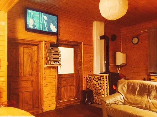 a living room with a couch and a television on a wall at Nexus Kulcsoshaz Bukkloka Gyimes in Făgeţel