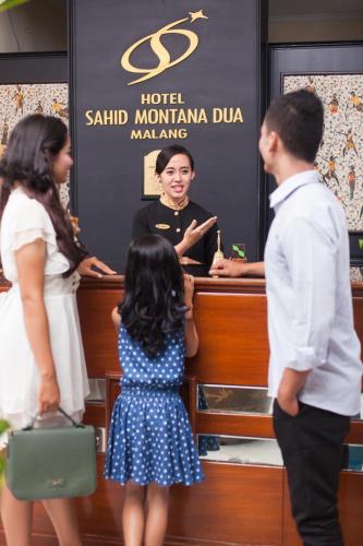 a little girl in a blue dress standing in front of a woman at Hotel Montana Dua Malang in Malang