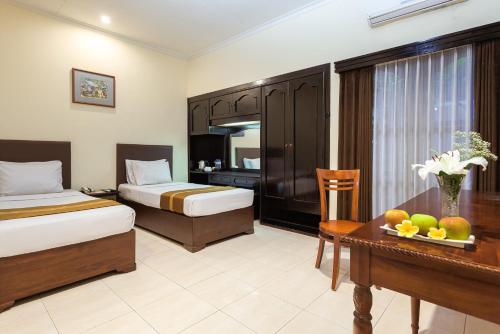 een hotelkamer met twee bedden en een tafel met fruit erop bij Hotel Montana Dua Malang in Malang