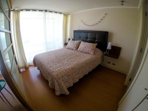 um quarto com uma cama e uma grande janela em Vista Meseta Coraceros em Viña del Mar
