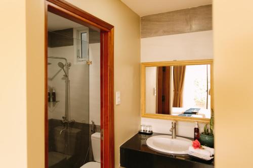 a bathroom with a sink and a shower and a mirror at Minh Nhung Hotel in Bao Loc