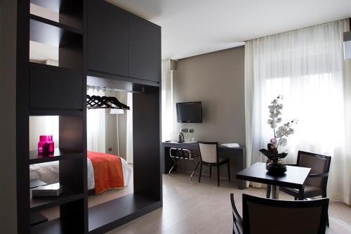 1 dormitorio con cama, escritorio y mesa en Zara Rooms & Suites, en Suzzara