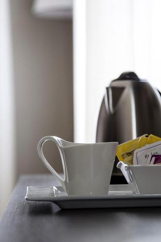 a coffee cup sitting on a plate with a tea pot at Zara Rooms & Suites in Suzzara