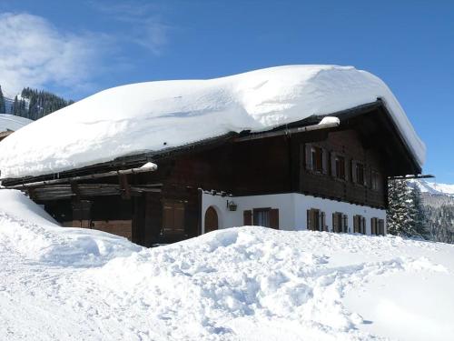 a snow covered building with a pile of snow at Alphüsli Garfrescha in Sankt Gallenkirch